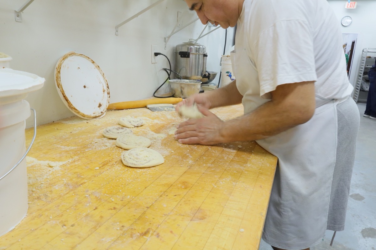 Master Baker Max shaping artisan loaf dough on butcher block